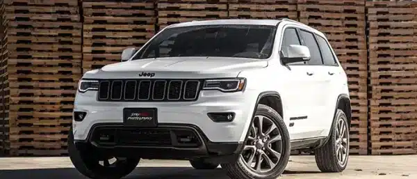 A white Jeep Grand Cherokee parked outdoors with vehicle systems and engine components that require diagnostic testing when performance drops.