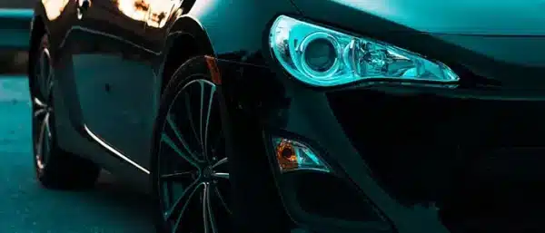 Close-up front view of a modified black sports car with custom wheels, representing aftermarket engine performance and vehicle tuning upgrades.